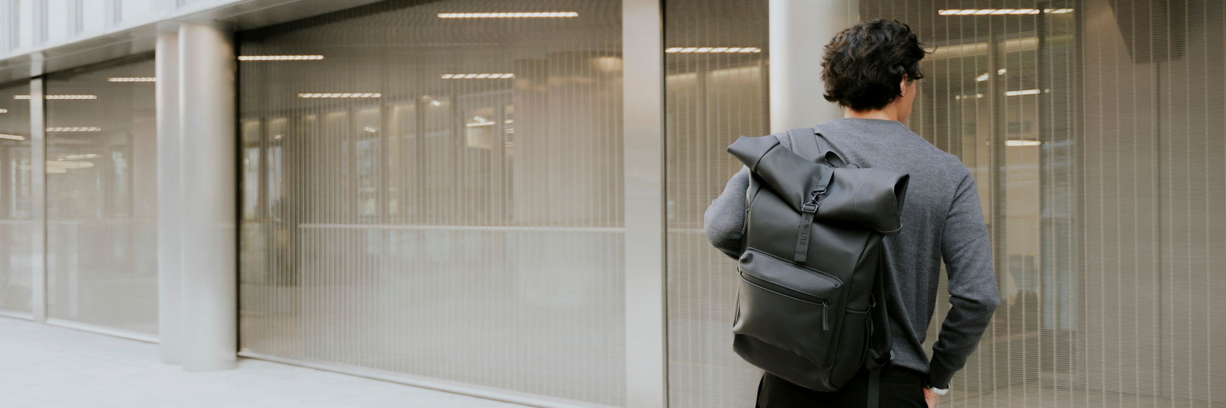 Empleado de espaldas con una mochila como regalo de empresa personalizado frente a oficinas