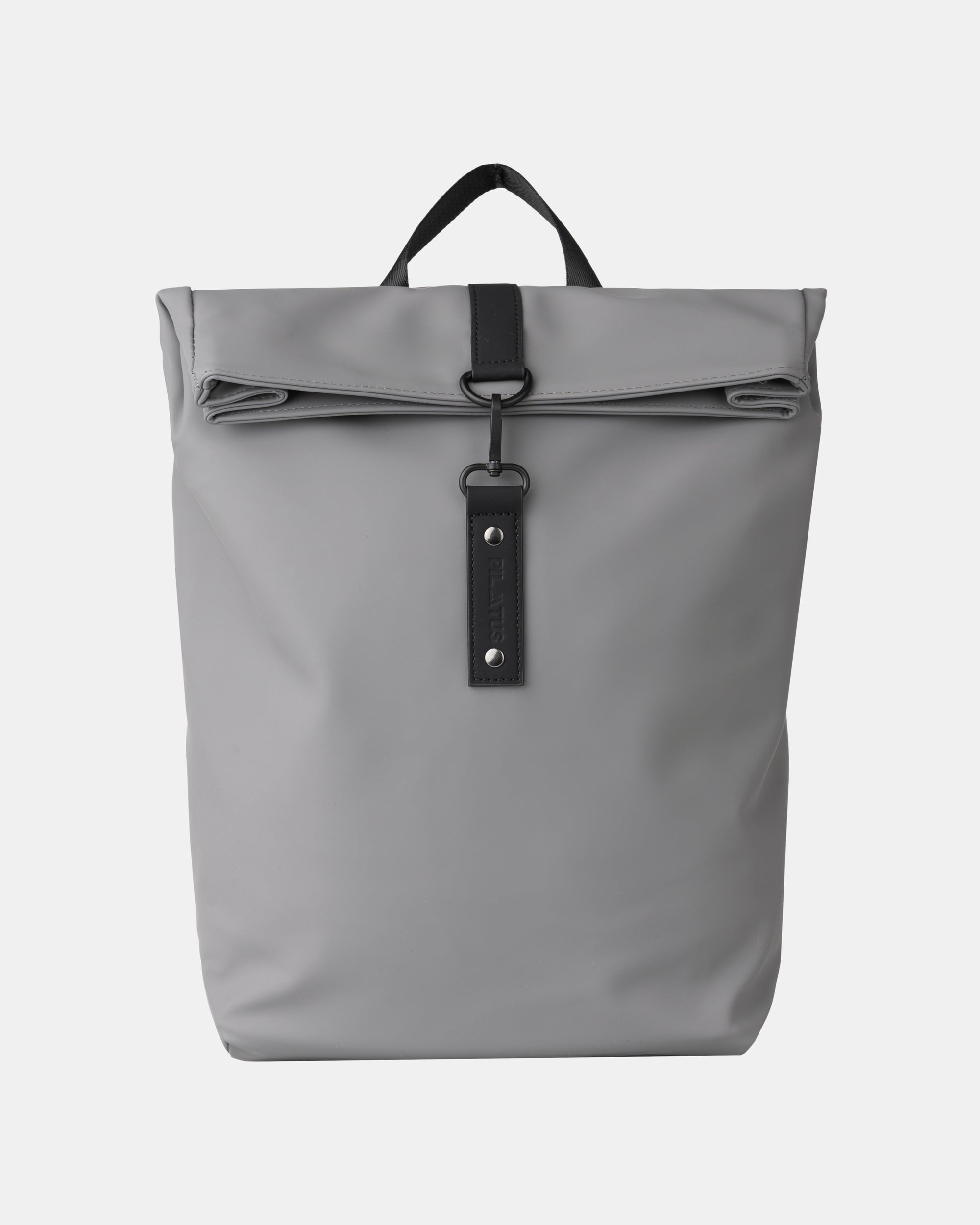 Mochila gris mate con cierre enrollable, tira vertical negra con gancho y asa superior. Texto: PILATUS