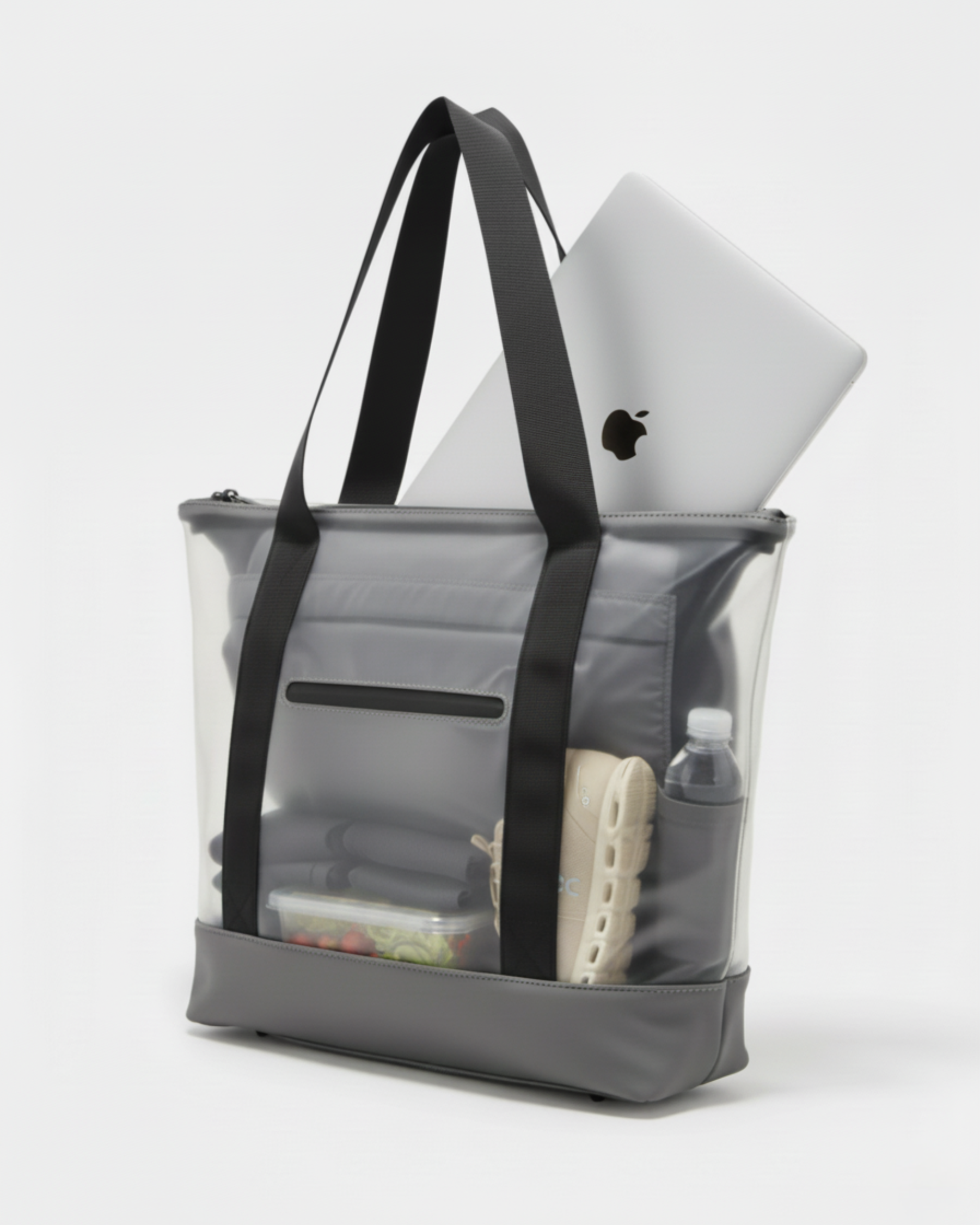 Tote bag transparente con ordenador, zapatillas de deporte, botella, un tupper y ropa de gimansio.