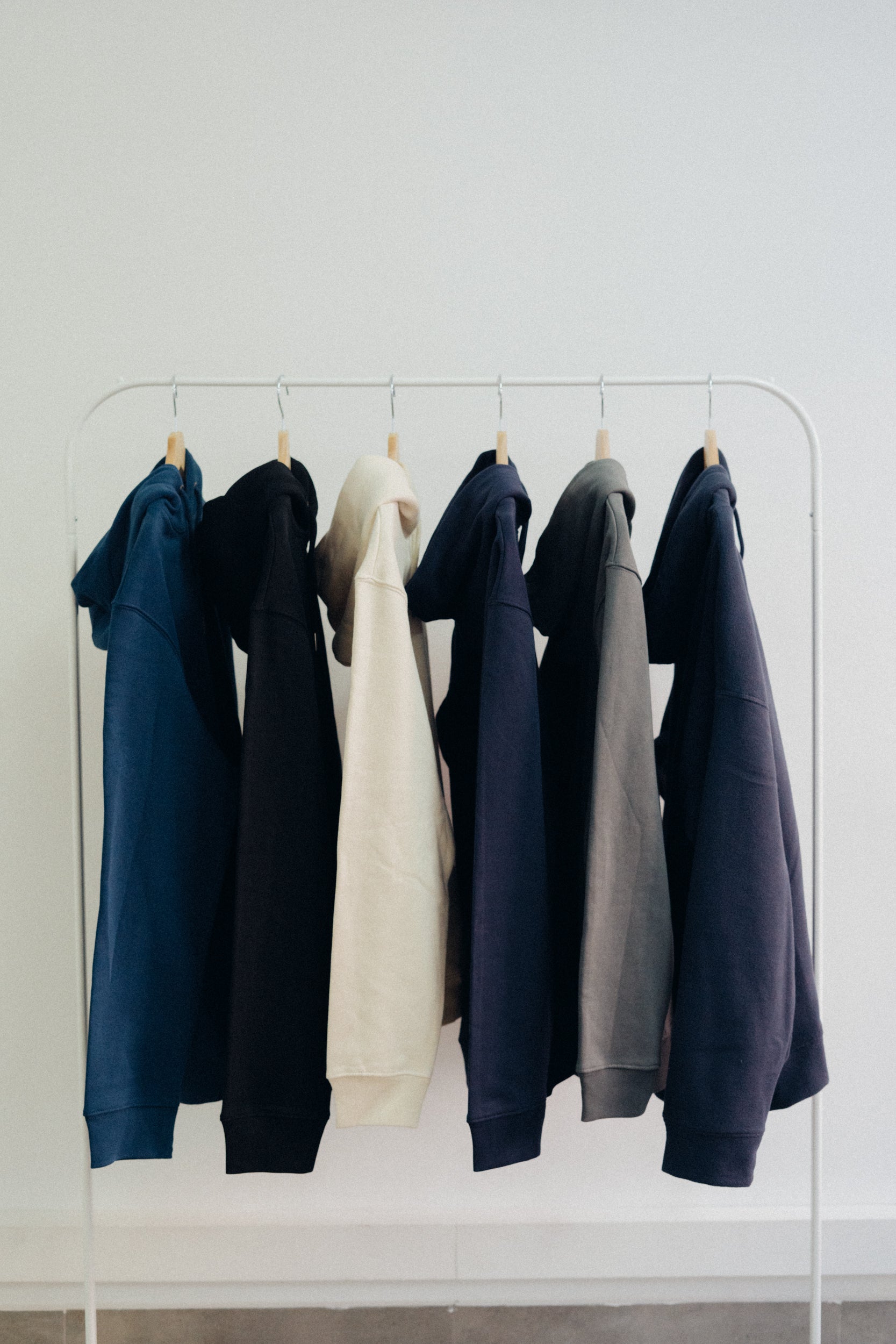 Sudaderas de distintos colores corporativas colgadas en perchas. 