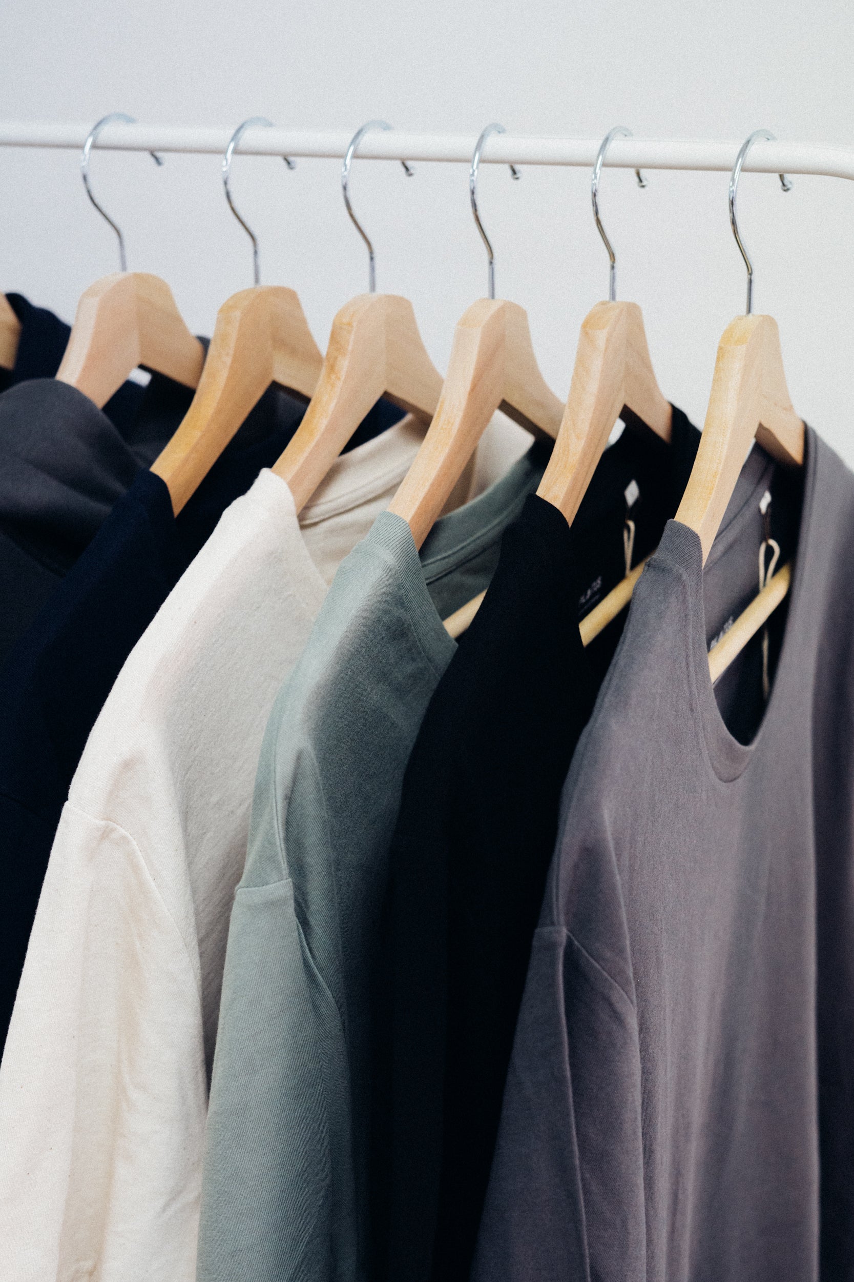 Camisetas de distintos colores corporativas colgadas en perchas.