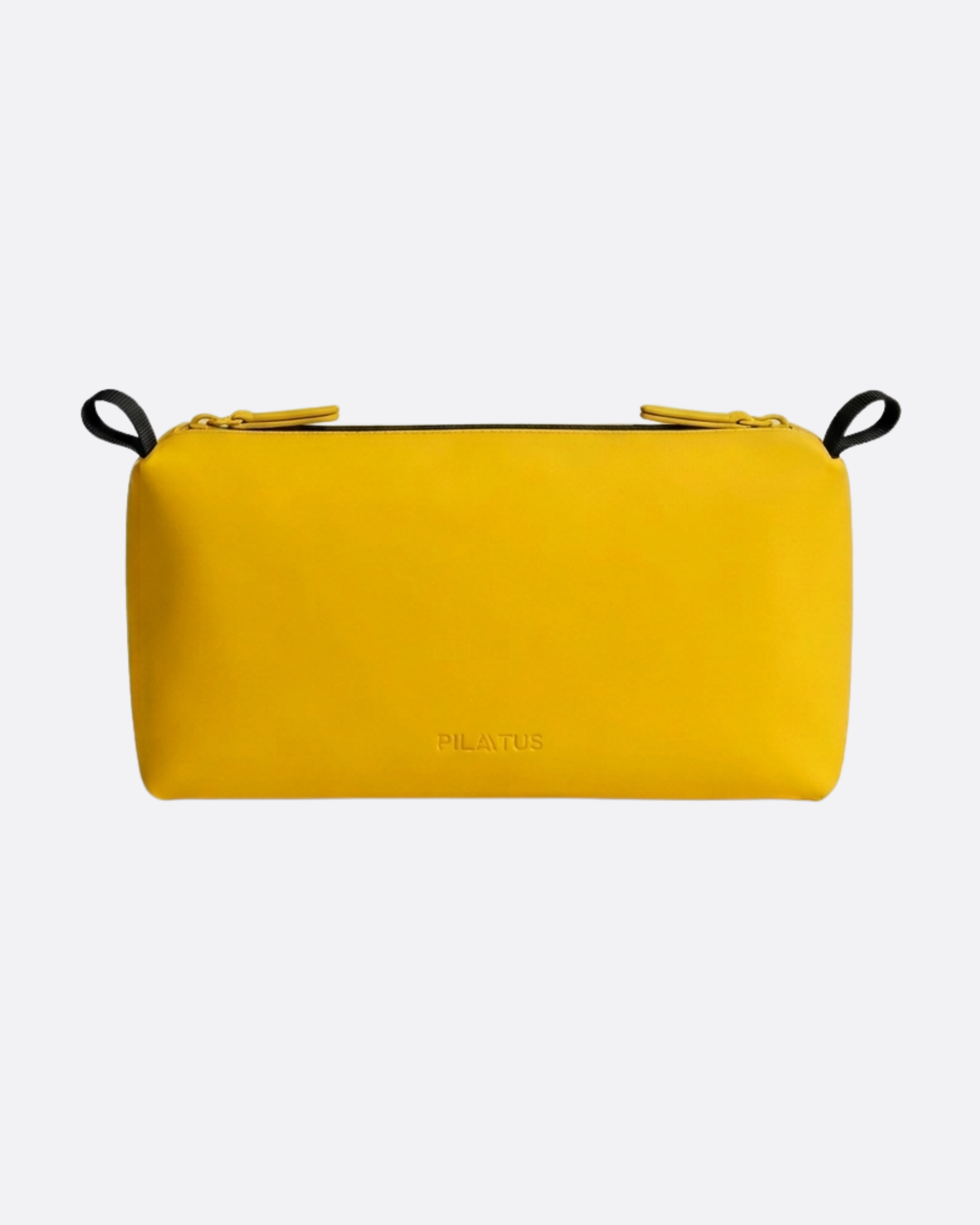 Neceser rectangular amarillo con cierre de doble tirador y asas negras laterales; fondo claro minimalista. Texto: PILATUS