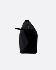 Neceser rectangular negro con cremallera superior y tira de agarre, mostrado de lado sobre fondo blanco minimalista