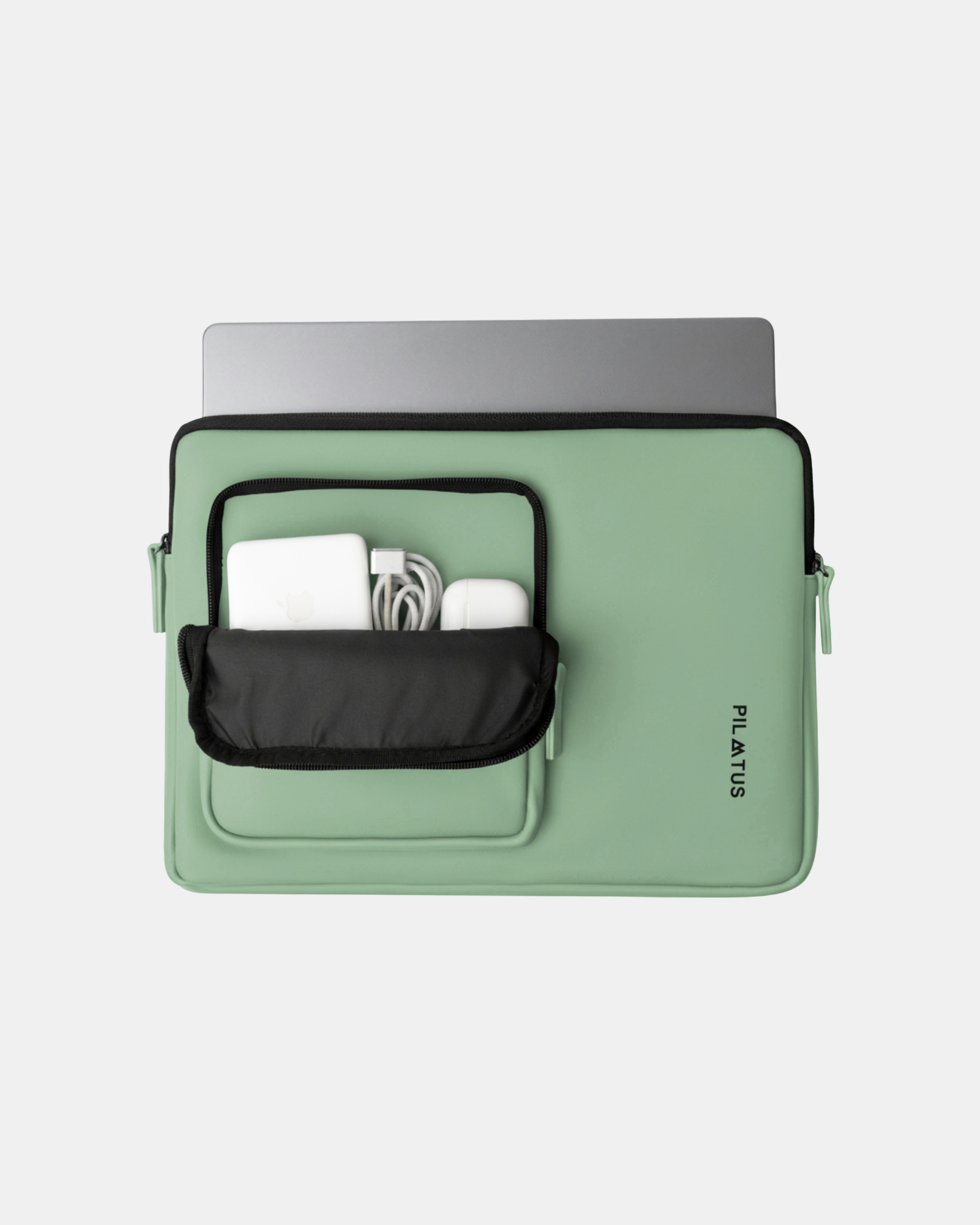Funda para portátil verde menta con bolsillo frontal negro abierto mostrando cargador, cable y AirPods. Texto: PILATUS