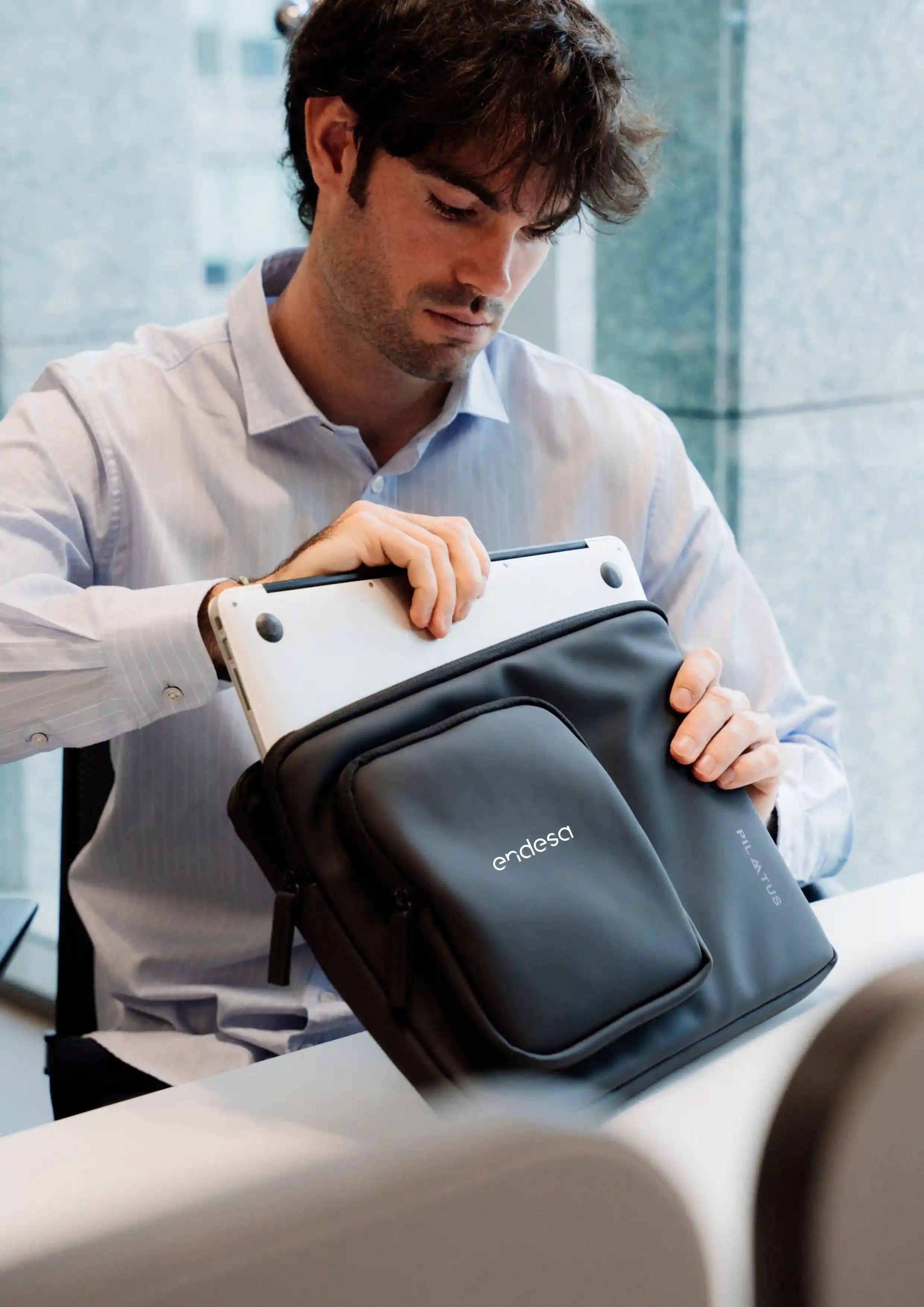 Hombre en oficina con el producto Urban Sleeve en color deep black con logotipo corporativo.