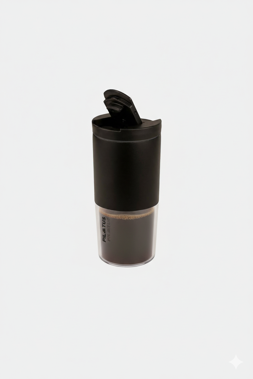 Termo de viaje negro con tapa abatible y base transparente que muestra líquido oscuro. Texto: PILATUS