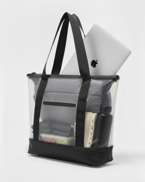 Bolsa tote transparente con asas negras; contiene un portátil plateado con logo Apple, botella negra, zapatillas beige