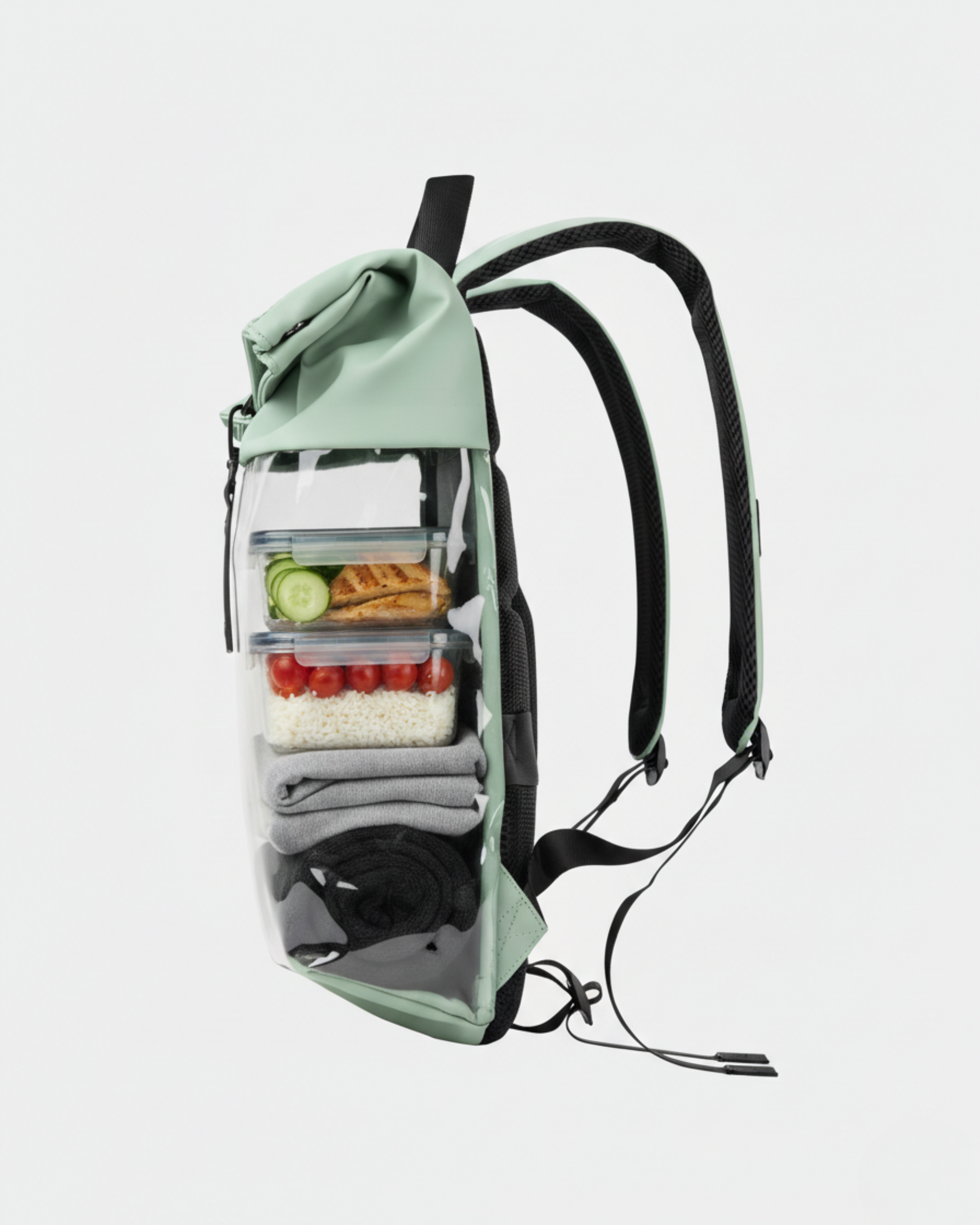 Mochila verde menta con frontal transparente mostrando tuppers (ensalada, tomates), ropa doblada en compartimentos