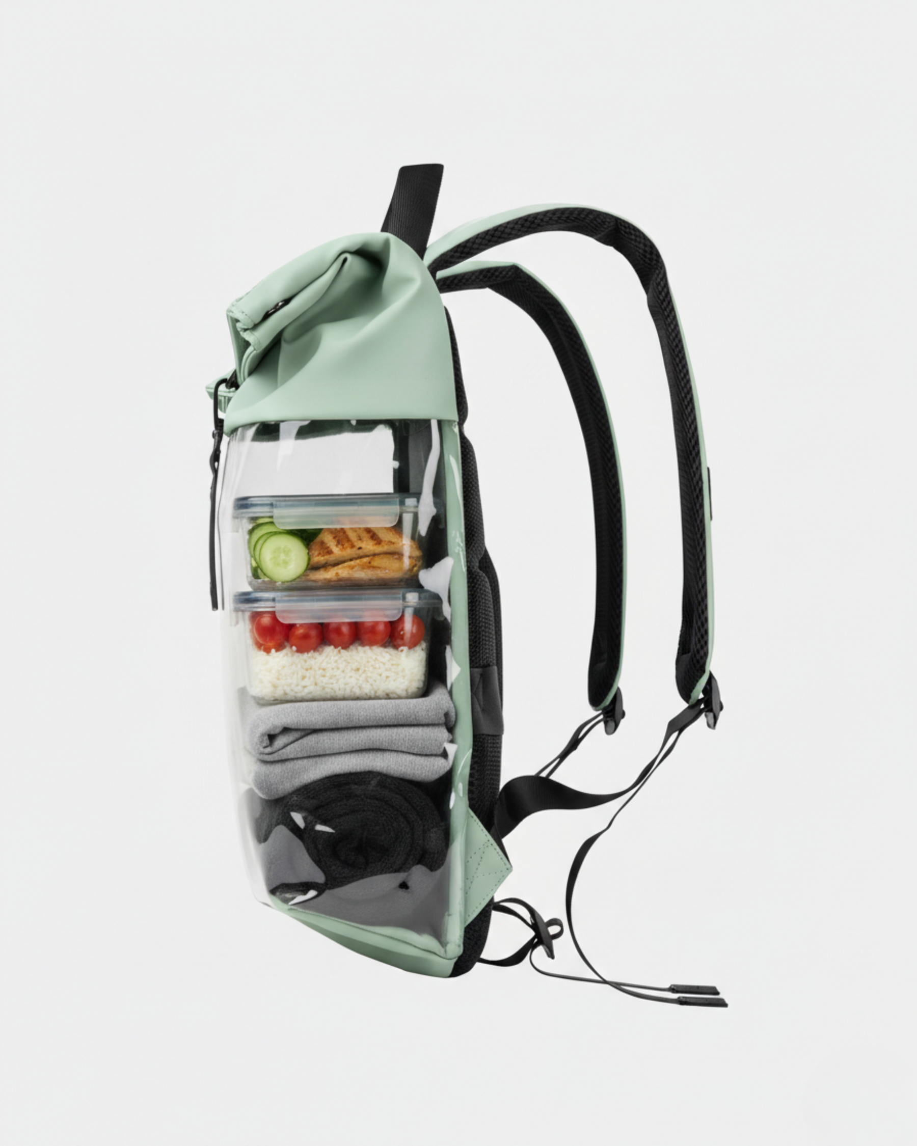 Mochila verde menta con frontal transparente mostrando tuppers (ensalada, tomates), ropa doblada en compartimentos